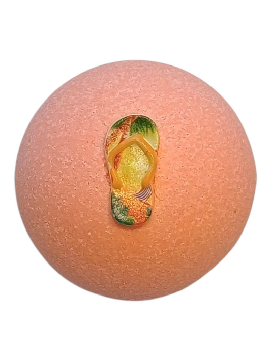 Peach coloured honeysuckle scent bath bomb with thongs on top